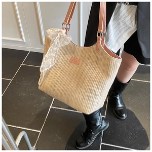 Detail of woven straw tote bag featuring pink leather straps and white lace ribbon deco