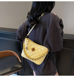 Detail of yellow quilted tote bag with golden chain and round metal twist lock