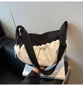 Detail of contrast color crossbody bag featuring white pleated design and black strap