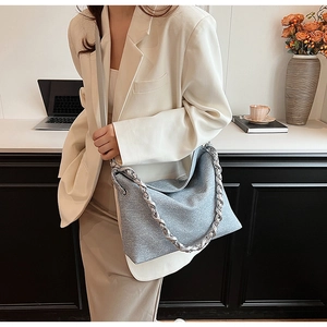 Detail of light blue textured hobo bag with silver chain and wide canvas strap on a model