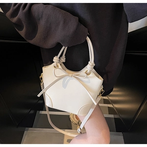 Detailed view of cream leather bucket bag with bow ornament and knotted handle detail