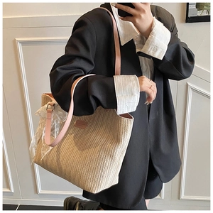 Detail of woven straw tote bag featuring pink leather straps and white lace bow accessory