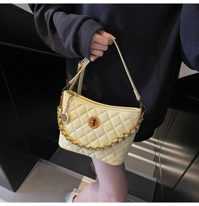 Close-up of cream quilted crossbody bag with gold twist lock and chunky chain detail