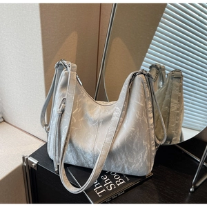 Close-up of silver-gray crinkled tote bag with metallic hardware and dual strap details