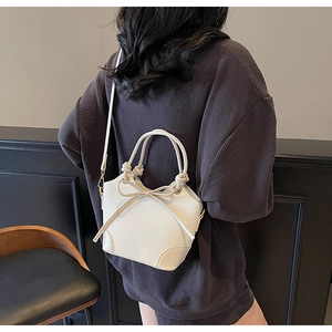 White bucket bag with bow detail and knotted handle shown on model in real-life setting