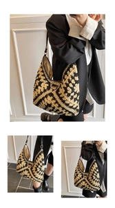 Detail of hand-woven straw tote bag with black geometric patterns and leather straps