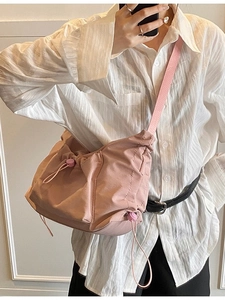 Pink nylon drawstring tote bag worn cross-body style showing the large capacity and texture