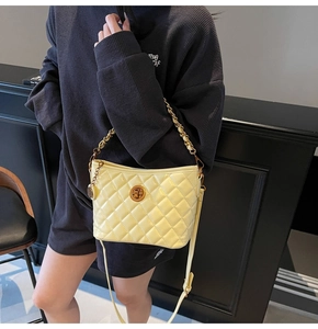 Close-up of pale yellow quilted tote bag featuring glossy finish and gold chain strap