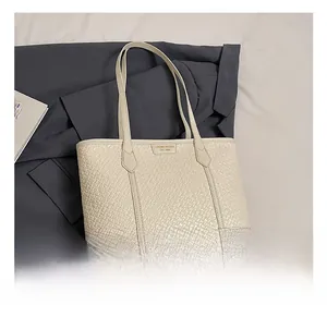 Gros plan du sac cabas beige tissé montrant la texture et le logo de la marque