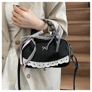 Close-up of black patent leather bag with lace trim and ribbon handle details