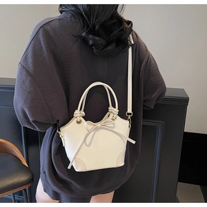 Detail of white bucket bag with elegant bow knot decoration and sleek metal hardware