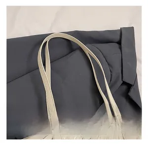 Gros plan sur la texture tressée et la bandoulière en cuir de ce grand sac cabas beige