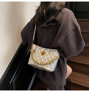 Detailed close-up of metallic silver quilted tote with gold chain strap and turn-lock