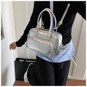 Detail of silver metallic Boston handbag featuring adjustable straps and fringe zipper