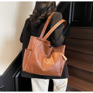 Detail of vintage brown tote bag with soft pleated texture and side pockets on a model