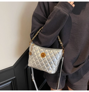 Detail of silver quilted bucket bag with metal twist lock and dual chain straps