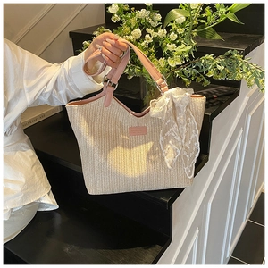 Detail of woven straw tote bag with pink leather straps and white lace ribbon decoration