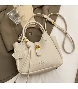Close-up of cream textured leather tote bag with dog charm and gold metal details