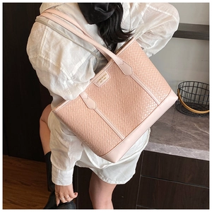 Détail du sac cabas rose avec texture tressée et plaque de marque métallique