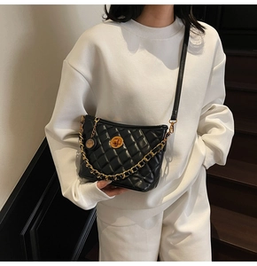 Detail of black quilted leather shoulder bag with gold twist lock and chain strap