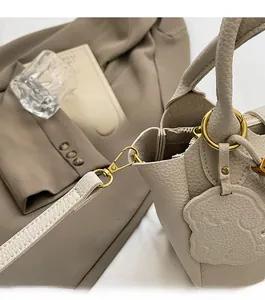 Detail of lychee textured leather tote with gold rings and cute bear pendant charm