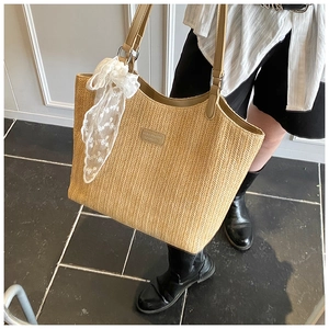 Detail of hand-woven straw tote with brown leather handles and a white lace bow