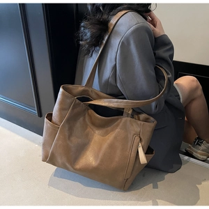 Detailed side view of large brown vintage faux leather tote bag with functional side pocket