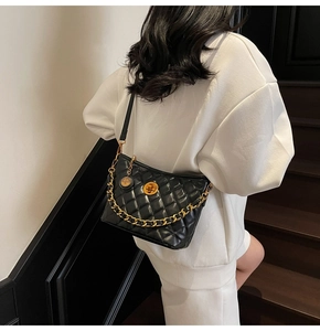 Detail of black quilted leather shoulder bag with gold chain and circular swivel lock