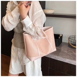 Détail du cabas tissé rose avec poignées en cuir porté par un mannequin en tenue décontractée