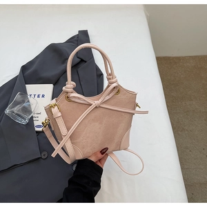 Detail of pink leather bucket bag with bow accent and suede patchwork texture
