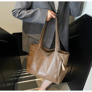 Close-up of brown leather tote bag showing side pocket and soft textured grain