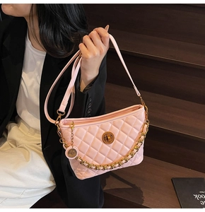Close-up of pink quilted crossbody bag with gold chain and rotary lock on wooden steps