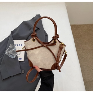 Close-up of contrast canvas bucket bag with leather bow and detachable shoulder strap