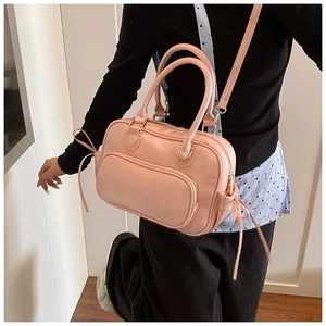 Detailed view of pink Boston bag with golden hardware and adjustable strap on a model