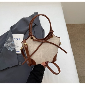 Macro view of canvas bucket bag with brown leather trim and metal hardware details