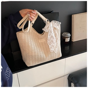 Detail of woven straw tote bag with cream handles and white lace scarf accessory