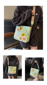 Detailed embroidery of sunflowers on a light green crossbody bag with patterned strap