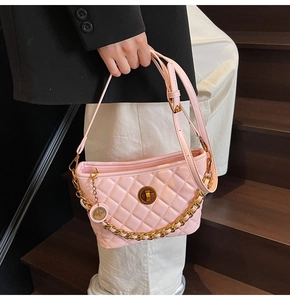 Detail of pink quilted tote bag featuring gold chain strap and rotary metal lock