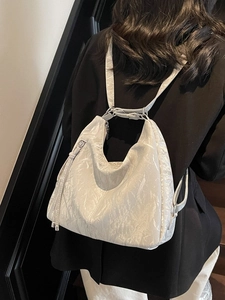 Minimalist white crinkled leather hobo backpack with glossy texture and metal ball tassel