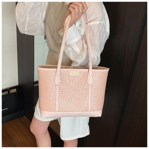 Détail du sac cabas rose clair tressé avec base en cuir et plaque logo dorée