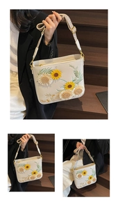 Detail of white leather shoulder bag featuring intricate sunflower floral embroidery