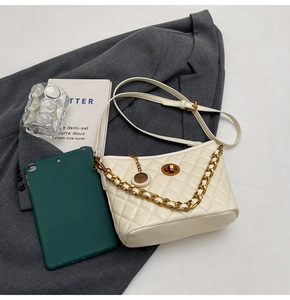 Detailed view of white quilted tote bag with gold chain strap and twist lock closure
