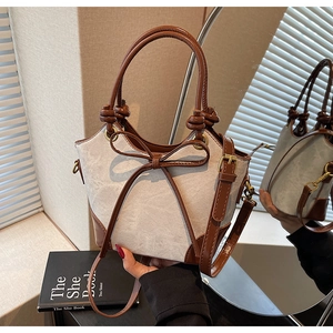 Detail of canvas bucket bag with leather bow decoration and stylish knotted handle