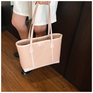 Détail du sac cabas rose à texture tressée avec logo doré et longues bandoulières