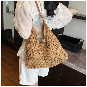 Detail of woven straw tote bag with diamond cutout patterns and slim leather shoulder strap