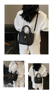 Detail of black pebbled leather handbag featuring gold clasp and cute dog charm accessory