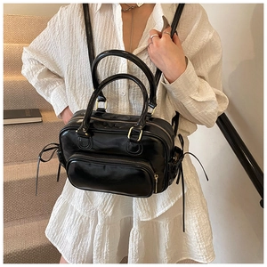 Detail view of a black glossy backpack showing golden zippers and versatile carry handles