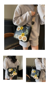 Detail of floral embroidery on black crossbody bag with ethnic style woven shoulder strap