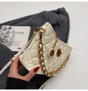 Detail of white quilted leather bag with chunky gold chain and swivel lock closure