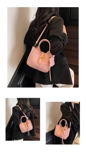 Detail of pink lychee leather handbag featuring gold hardware and bear charm